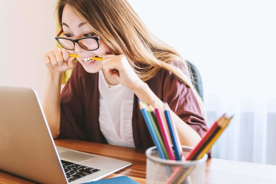 Asian woman is biting pencil in frustration to using her laptop